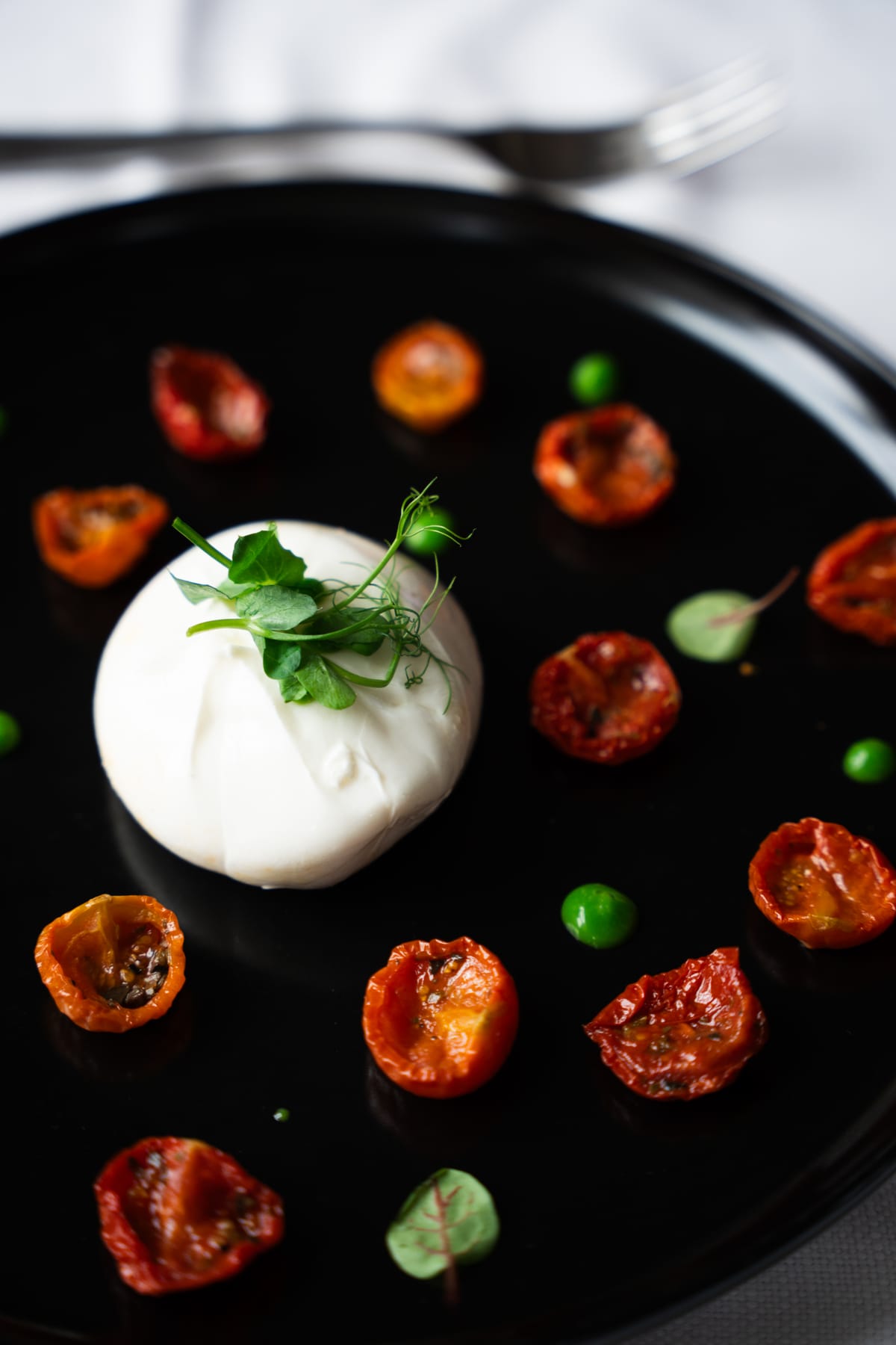 Burrata with confit cherry tomatoes on a black plate