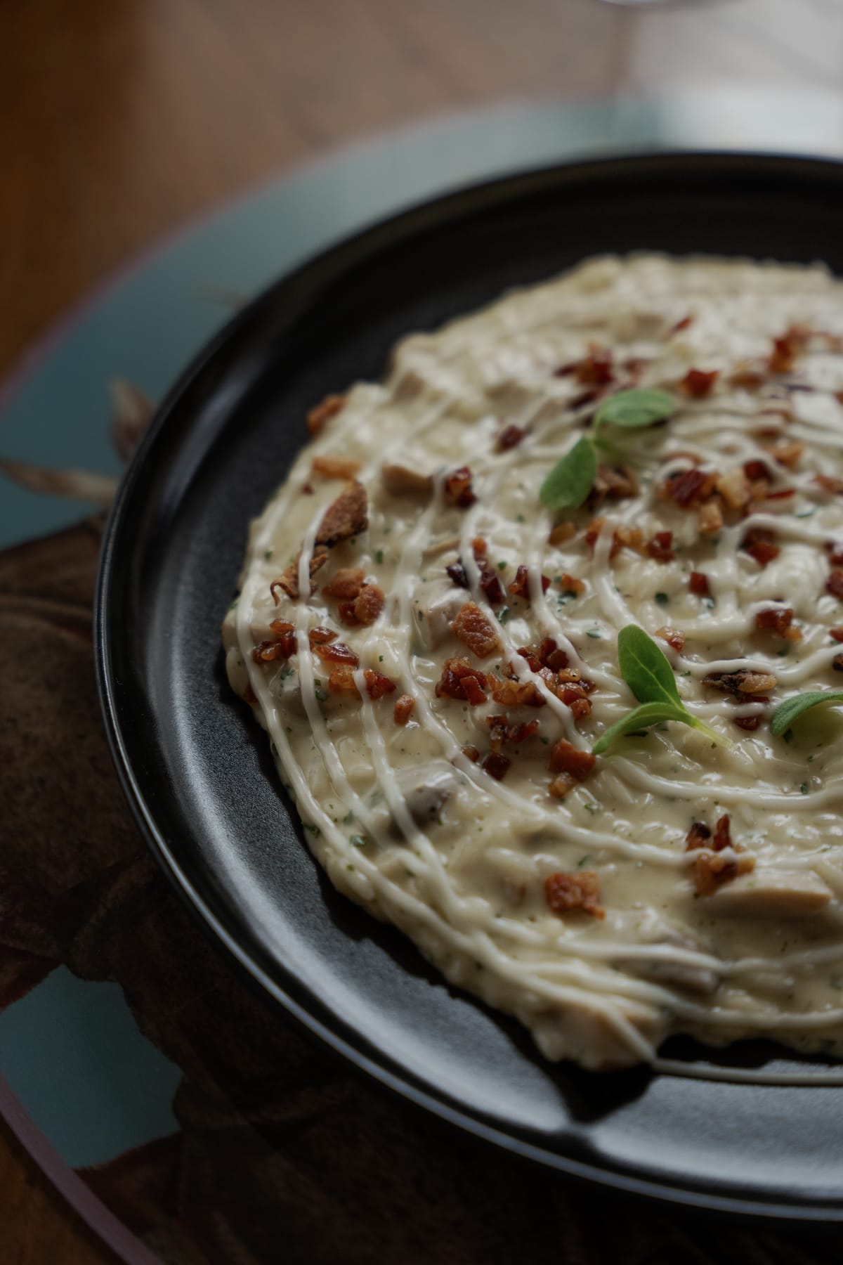 Piatto cremoso con briciole croccanti e foglie di basilico su piatto nero